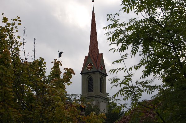 Kirchturm der Kirche Kirchdorf umrahmt von Blätterwerk.