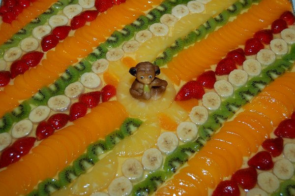 Nachaufnahme einer Süssspeise, garniert mit Bananen, Kiwis, Pfirsich, Ananas und Erdbeeren.