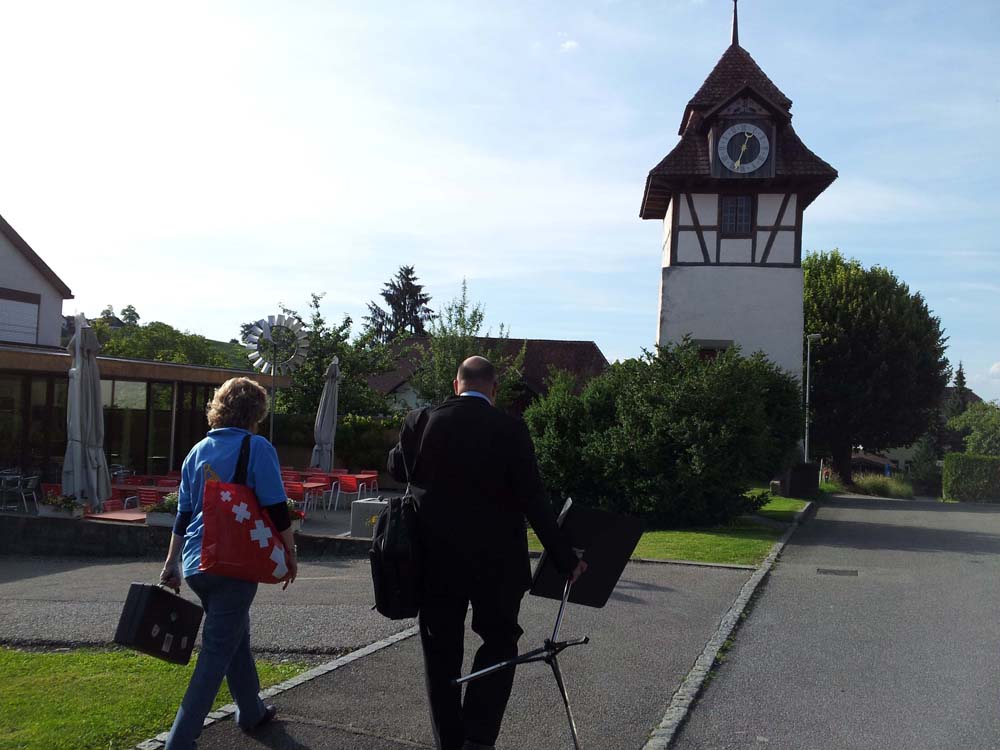 Zwei Personen gehen im Gegenlicht auf den Turm beim Altersheim zu.
