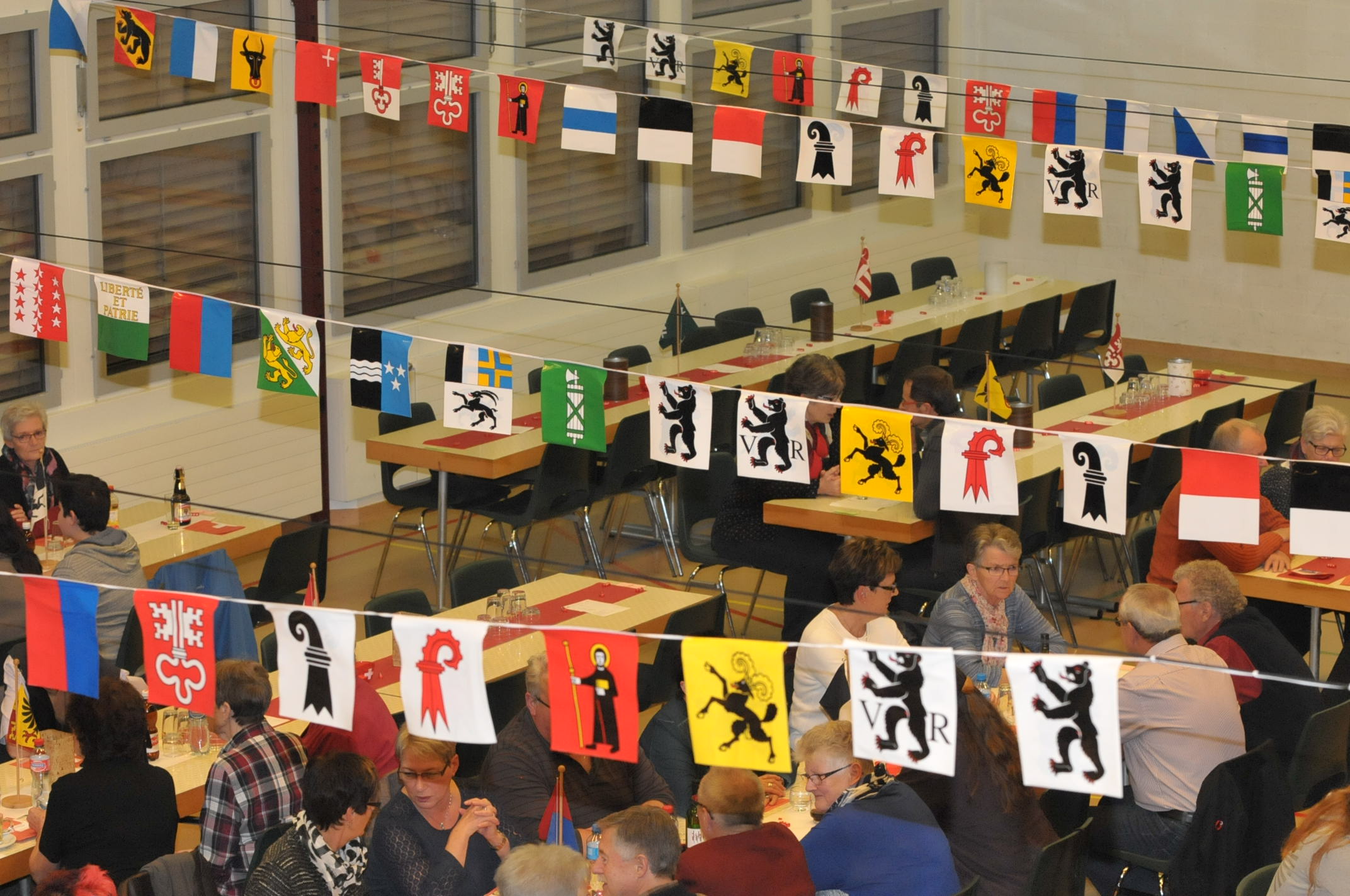 Blick über den Zuschauerraum von der Galerie aus. Es sind diverse Kantonsfähnchen von der einen auf die andere Seite gespannt.