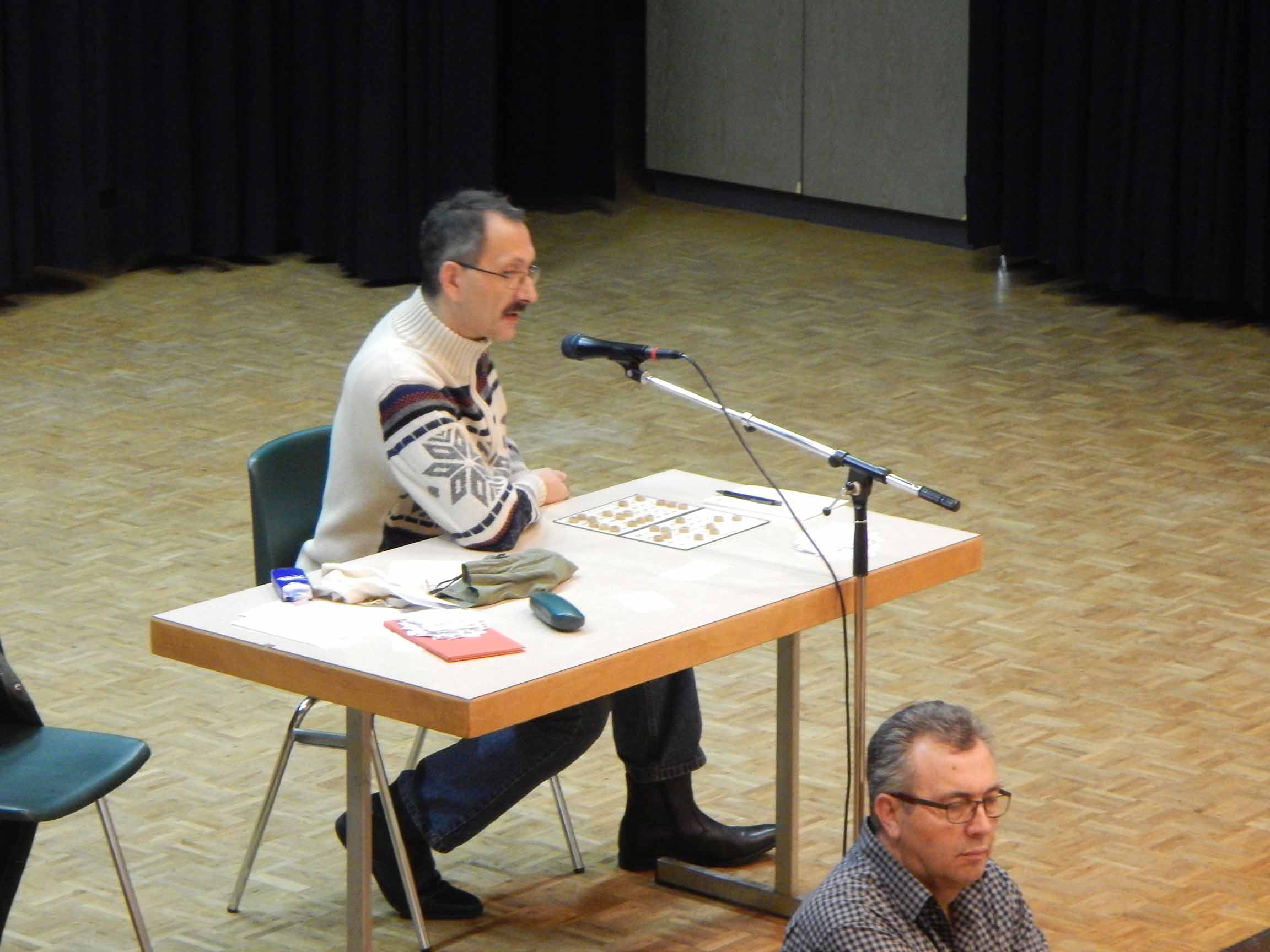 Speaker Hans Dänzer am Tisch auf der Bühne.