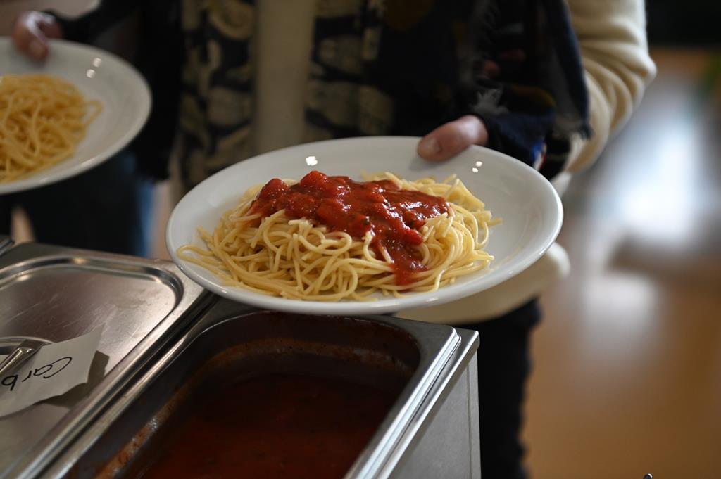 Ein Teller Spaghetti in der Hand einer Besucherin.